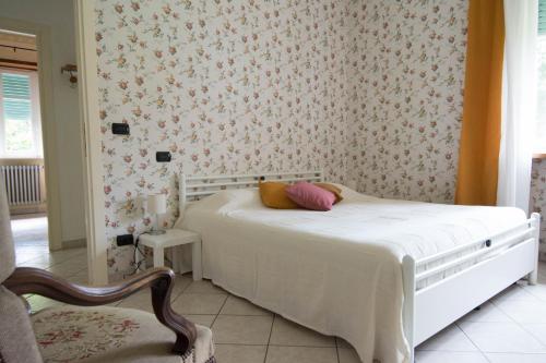 a bedroom with a white bed with a floral wallpaper at La Casa di Bianca in SantʼAmbrogio di Torino