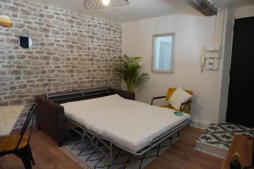 un lit dans une chambre avec un mur de briques dans l'établissement Appartement en plein centre, à Avignon