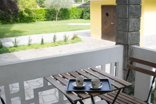 eine Holzbank mit zwei Tassen auf einem Tablett auf einem Balkon in der Unterkunft La Casa di Bianca in SantʼAmbrogio di Torino