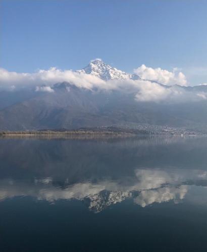 a mountain with a reflection in the water with clouds at Casa Vacanze Linda in Gera Lario