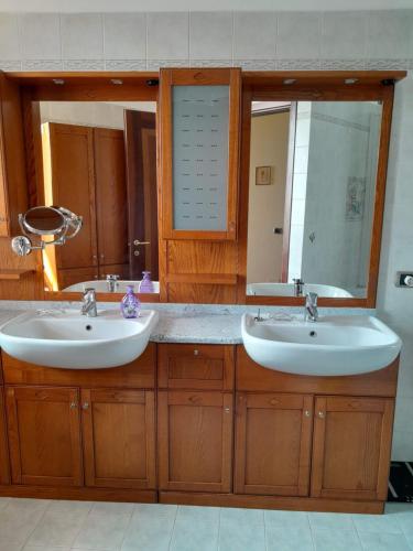 baño con 2 lavabos y espejo grande en Tramonto al Lago, en Gavirate