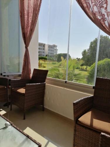 uma sala de estar com cadeiras e uma grande janela em Marina golf em Asilah