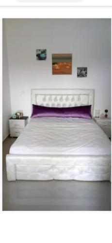 um quarto com uma cama branca e uma almofada roxa em Marina golf em Asilah