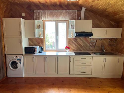 喬爾蓬阿塔的住宿－Lakeside Villa Issyk Kul，厨房配有白色橱柜、水槽和窗户。