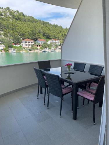 a table and chairs on a balcony with a view of the water at Apartman OZANA in Blace