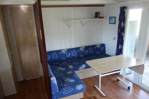 un salon avec un canapé bleu et une table dans l'établissement Mobil Home sur la côte landaise, à Saint-Julien-en-Born