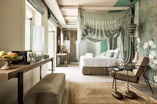 Niove Suites Milos في بلاكا ميلو: غرفة نوم بسرير واريكة وطاولة