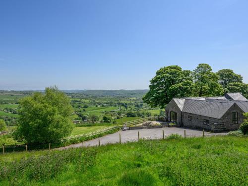 an old barn on a hill with a road at The Barn at Hill House in Buxton