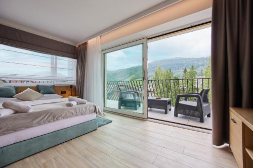 a bedroom with a bed and a balcony with a view at EveRest Apartamenty Szczyrk in Szczyrk