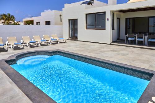 una piscina con sedie e una casa di 205 - Casa Santuario By Villas Now Ltd a Playa Blanca