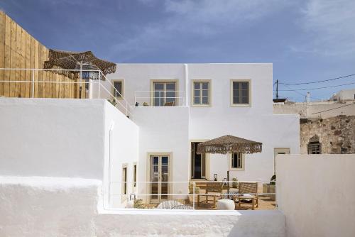 een wit huis met een tafel en stoelen bij Niove Suites Milos in Plaka Milou