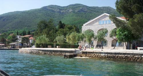 a building next to a body of water with mountains at Apartments Villa Danilovic in Herceg-Novi