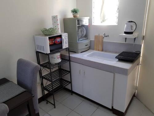 uma cozinha com um balcão com um micro-ondas e um lavatório em Entire Unit Fully Air-conditioned with Hi-Speed WiFi em Mabalacat