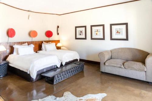 a hotel room with two beds and a couch at Zebula Boutique Hotel in Mabula