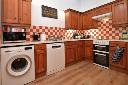 a kitchen with wooden cabinets and a washer and dryer at Cairnbaan House in Cairnbaan