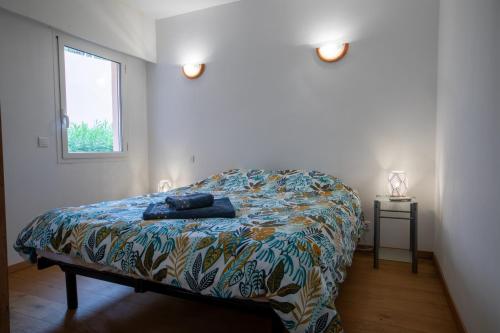 une chambre avec un lit avec une couette colorée et une fenêtre dans l'établissement Appartement dans résidence pieds dans l’eau, au Trayas