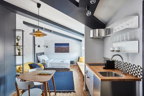 a kitchen and living room with a sink and a table at Bez Kantów Art Rooms in Warsaw