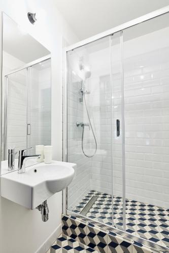 a white bathroom with a sink and a shower at Bez Kantów Art Rooms in Warsaw