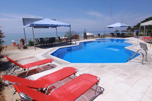 uma piscina com duas espreguiçadeiras vermelhas em Corfu Glyfada Menigos Resort Home 72 em Glyfada