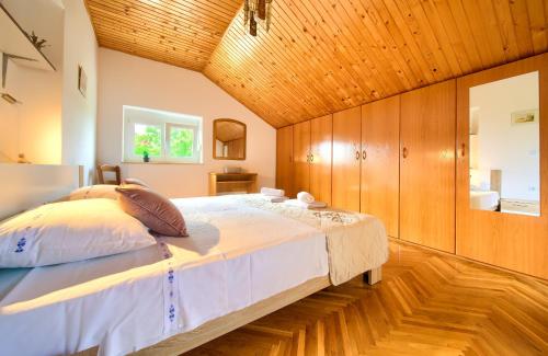 ein Schlafzimmer mit einem großen Bett und einer Holzdecke in der Unterkunft Apartment Lipovac in Malinska