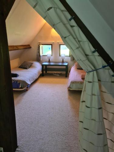 a attic bedroom with two beds and a table at Petite Maison de campagne in Fauguernon