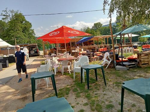 a man standing in front of tables and chairs at mobil-home du lac de Foix in Foix