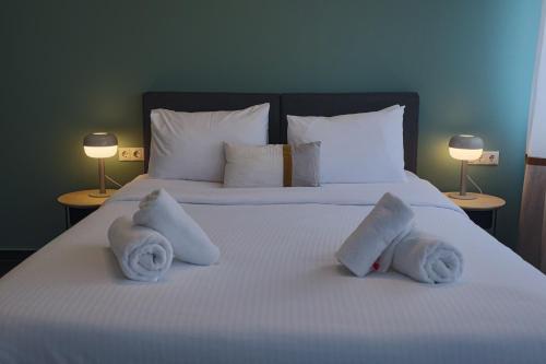 a large white bed with towels on it with two lamps at Elite Ermou Suites in Athens