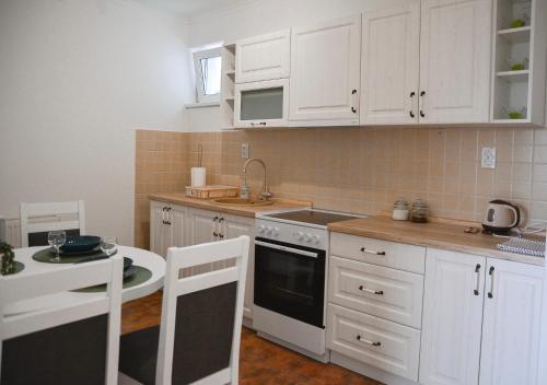 a kitchen with white cabinets and a sink and a table at CROWN apartment 2 in Subotica