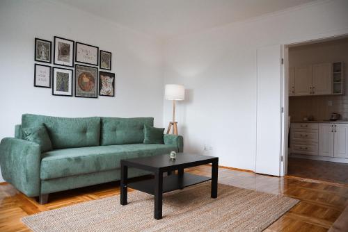 a living room with a green couch and a table at CROWN apartment 2 in Subotica
