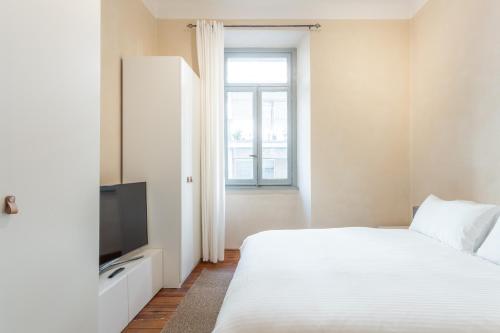 a bedroom with a white bed and a television at Suite Cavour by iCasamia in Varese