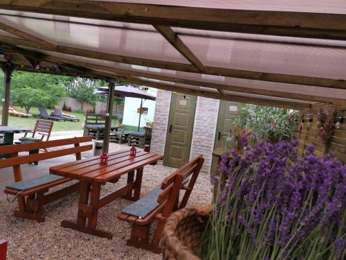 a patio with wooden benches and purple flowers at Berkó Vendégház in Rákóczifalva