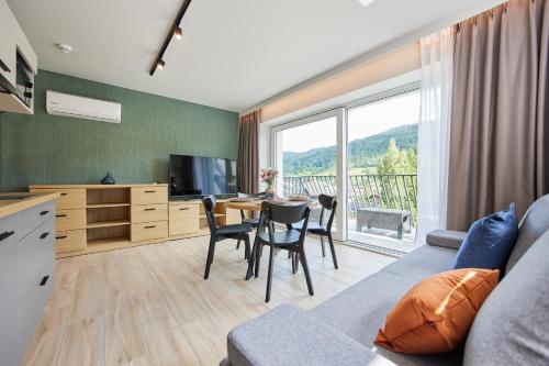a living room with a couch and a table with chairs at EveRest Apartamenty Szczyrk in Szczyrk