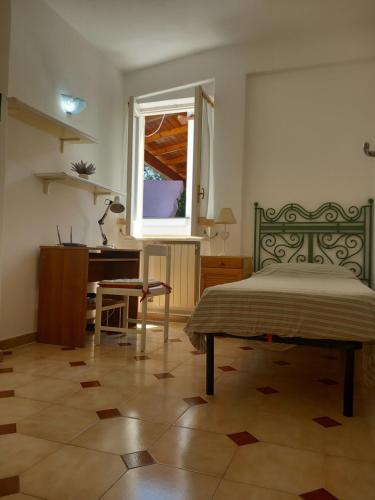 Villetta Panoramica في ايسكيا: غرفة نوم بسرير ومكتب ونافذة