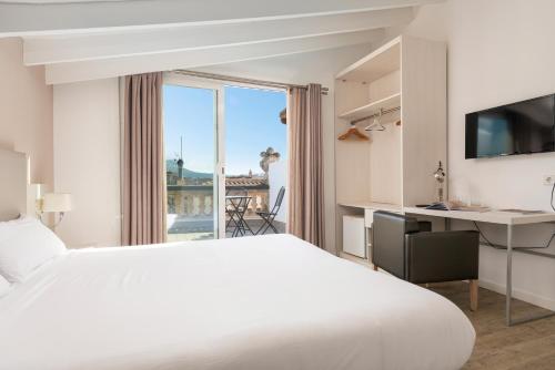 a hotel room with a bed and a desk and a window at HBE Boutique España - Turismo de Interior in Llucmajor