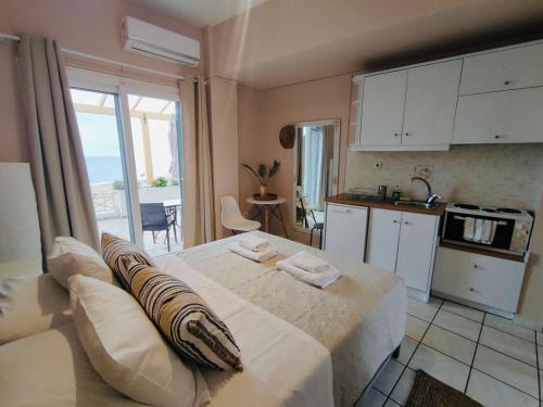 a bedroom with a large bed and a kitchen at Nereides Apartments in Agios Gordios