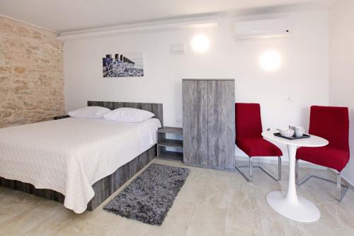 a bedroom with a bed and two red chairs at Luxory D-Rooms in Vela Luka