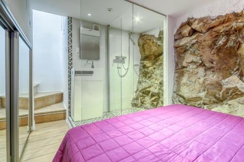 ein Schlafzimmer mit einem rosa Bett und einer Steinmauer in der Unterkunft Gauguin 44 Almadrava Roses - Immo Barneda in Roses