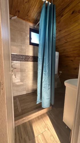 a bathroom with a shower with a blue shower curtain at Casa de lemn 2,Tip A in Corbu