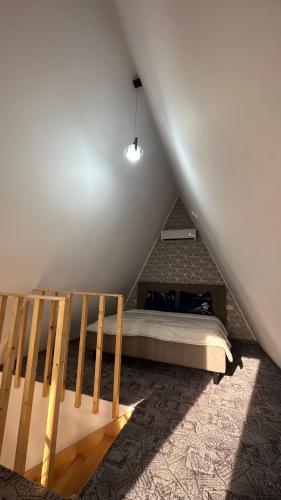 a bedroom with a bed and a staircase in a attic at Casa de lemn 2,Tip A in Corbu