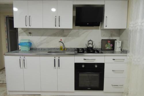 a kitchen with white cabinets and a black oven at Mavi Apart in Demre