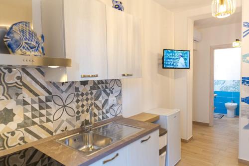 uma cozinha com um lavatório e uma televisão na parede em Sea Garden Apartments em Ascea