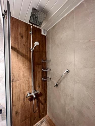 a shower in a bathroom with a wooden wall at ViLLA CLUB KONAK 10 in Alanya