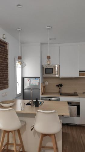 a kitchen with white cabinets and white stools at Atocha Suite in Madrid