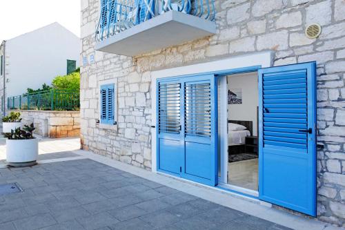 a stone house with blue doors and a balcony at Luxory D-Rooms in Vela Luka
