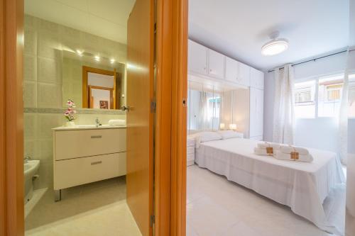 a bedroom with two beds and a sink and a mirror at HomeHolidaysRentals Caliz - Costa Barcelona in Pineda de Mar