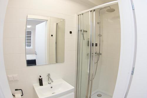 a white bathroom with a sink and a shower at Komfi Dom 2 in Rzeszów