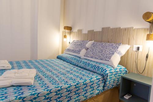 um pequeno quarto com uma cama com lençóis azuis e brancos em Sea Garden Apartments em Ascea