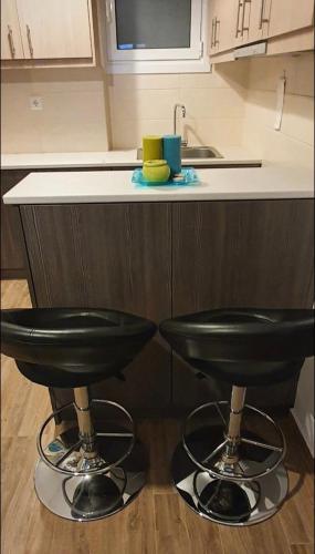a kitchen with two black stools in front of a counter at Loutraki by the sea in Loutraki