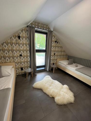 米托彭督比耶羅的住宿－CHALETY MÝTO POD ĎUMBIEROM，阁楼卧室配有2张床和白色地毯。