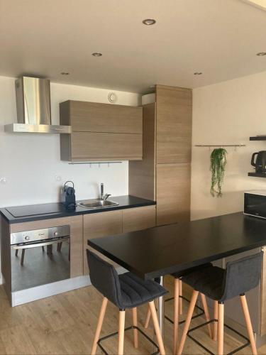 une cuisine avec une table et des chaises noires dans l'établissement Les pieds dans l'eau, à Saint-Quay-Portrieux